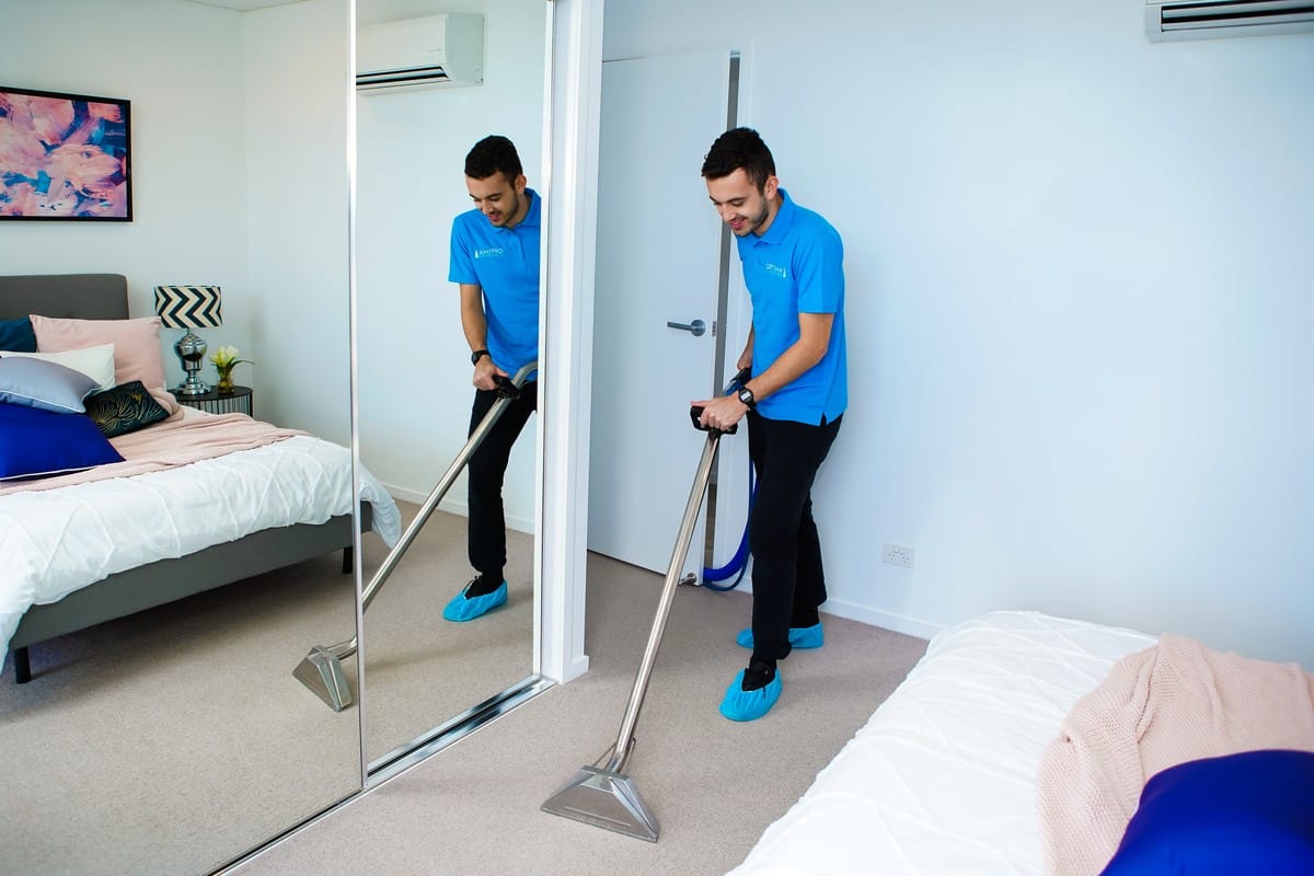 Optima Cleaners technician hot water extraction cleaning a bedroom carpet