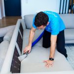 Optima Cleaners technician hot water extracting a light grey fabric sofa