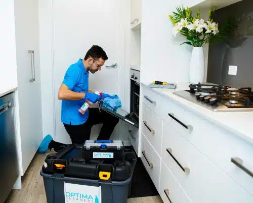 Optima Cleaners technician cleaning an oven in a home kitchen