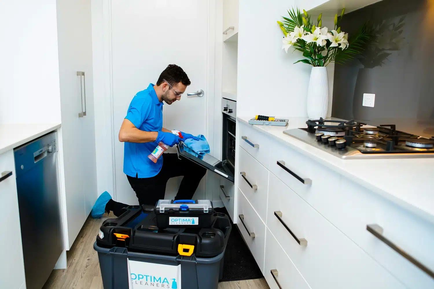 Optima Cleaners technician cleaning an oven in a home kitchen