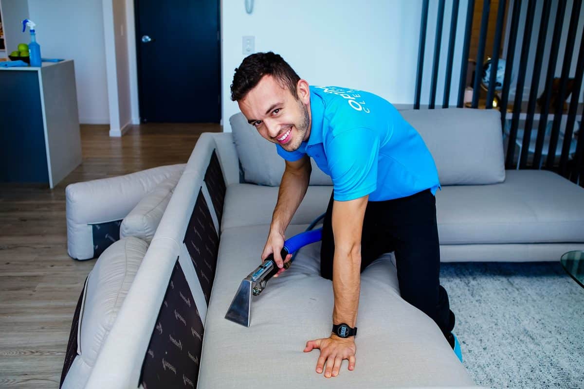 Technician re-extracting a sofa cushion, the fix for stains that reappear after sofa cleaning