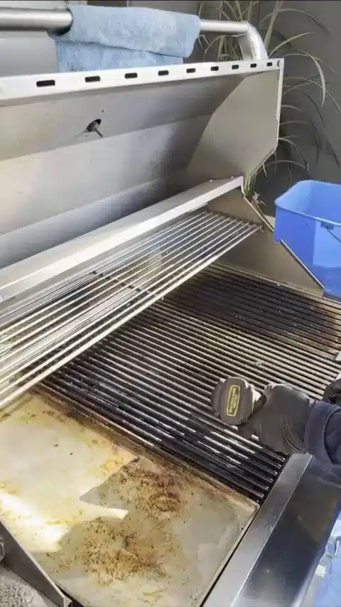 Technician using a drill brush to clean BBQ grill grates